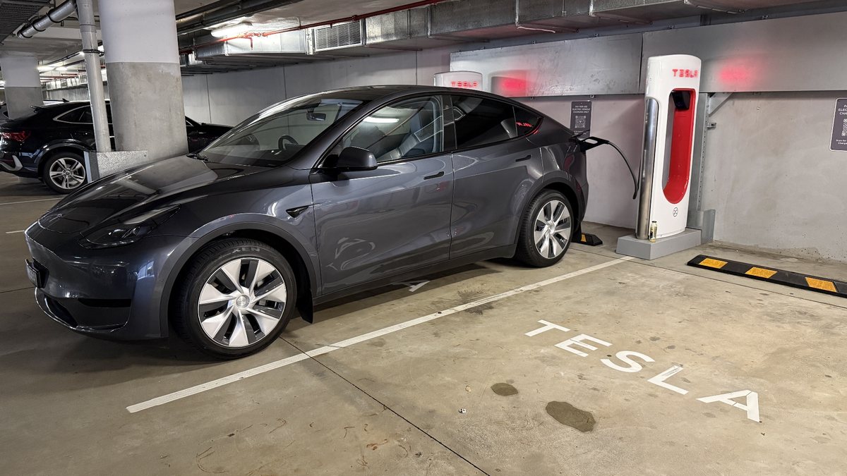 Photo: a grey current-shape Tesla Model Y plugged into a Supercharger in an underground car park in Western Australia