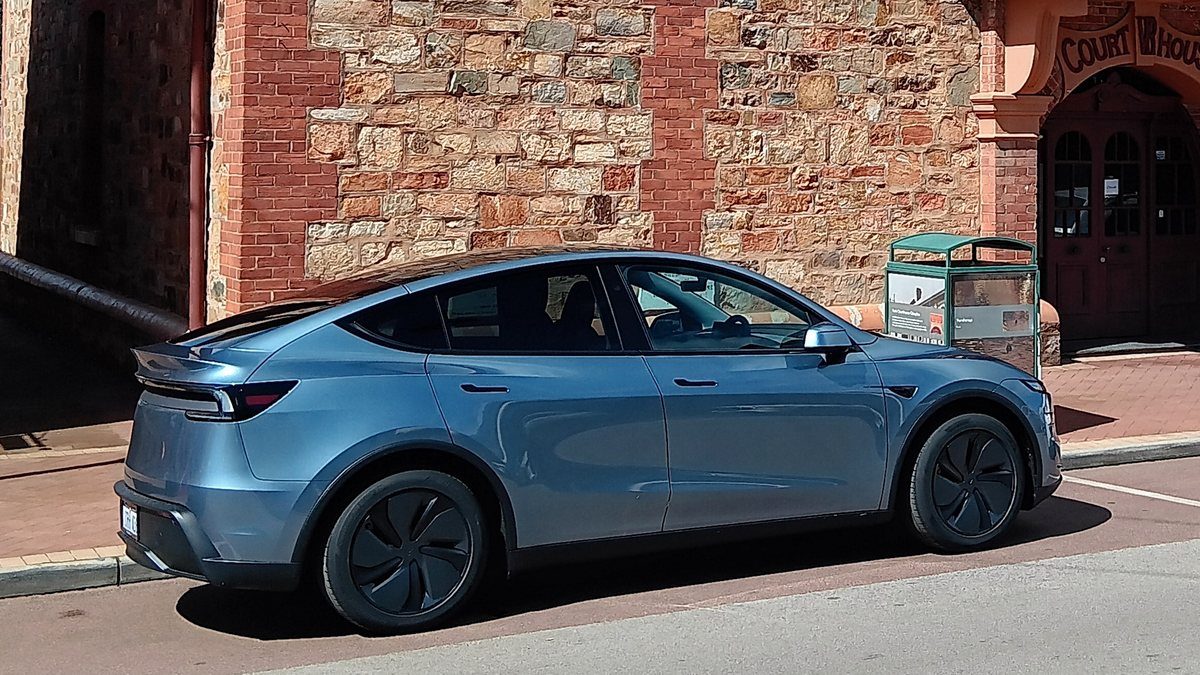 Photo: a blue Tesla Model Y parked outside a brick and stone courthouse